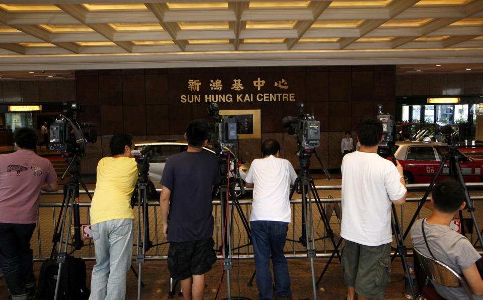 Journalists stand outside the Sung Hung Kai headquarters building in Hong Kong Friday, May 4, 2012. The former chief executive of Hong Kong developer Sun Hung Kai Properties Ltd. was arrested Thursday night in a high profile anti-corruption probe that has already targeted his billionaire brothers and a top official. (AP Photo/Kin Cheung)