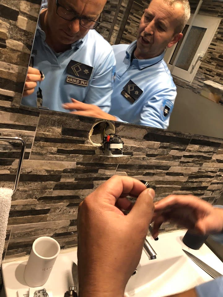 Photo of police tending to a hidden wall camera in a Portugal apartment. 