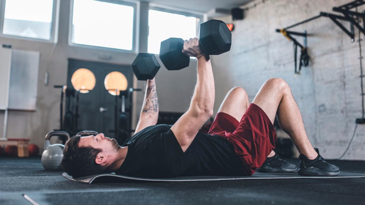  Man doing dumbbell chest press on the floor 