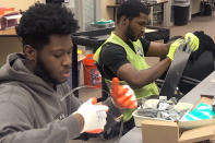 In this Jan. 16, 2020 photo, Nicholas Thomas, left, and Joe Wright, right, prepare school safety signs as part of the AmeriCorps Urban Safety Program at Wayne State University's Center for Urban Studies. Volunteers will post the signs and also help board up vacant houses Monday near a Detroit school as part of an annual project commemorating the Rev. Martin Luther King Jr's birthday and the federal holiday. (AP Photo/Corey Williams)