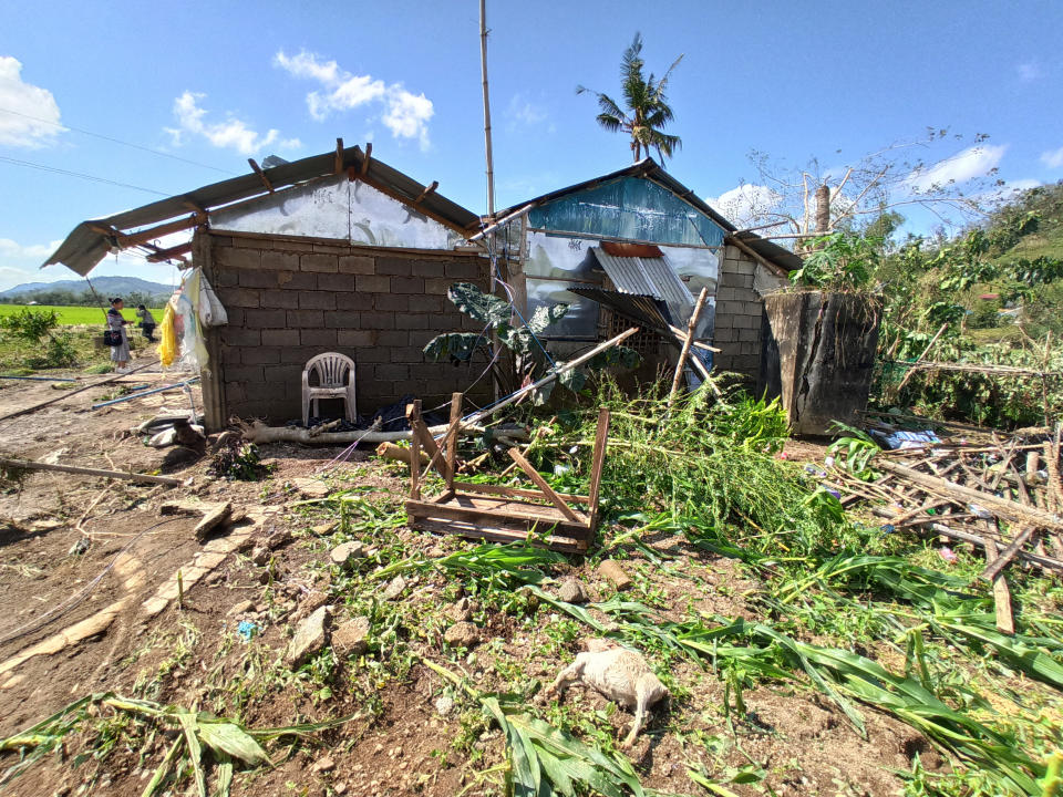 People walk beside homes damaged by Typhoon Phanfone at Batad Town, Iloilo province, central Philippines on Thursday Dec. 26, 2019. A strong typhoon that barreled through the central Philippines left at least 20 people dead and forced thousands to flee their homes, devastating Christmas celebrations in the predominantly Catholic country. (AP Photo/Leo Solinap)