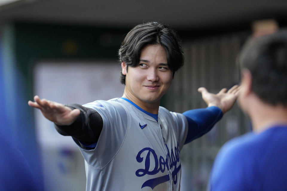 Los Angeles Dodgers' Shohei Ohtani stretches in the dugout during the first inning of the team's baseball game against the Cincinnati Reds on Friday, May 24, 2024, in Cincinnati. (AP Photo/Jeff Dean)