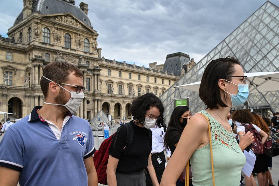 Tourists wearing protective face masks walk past the Louvre Pyramid (Pyramide du Louvre) designed by Ieoh Ming Pei, at the Cour Napoleon, in Paris, on August 15, 2020. (Photo by BERTRAND GUAY / AFP) / RESTRICTED TO EDITORIAL USE - MANDATORY MENTION OF THE ARTIST UPON PUBLICATION - TO ILLUSTRATE THE EVENT AS SPECIFIED IN THE CAPTION (Photo by BERTRAND GUAY/AFP via Getty Images)