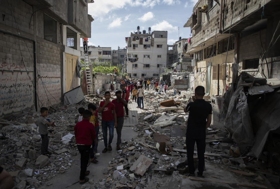 Palestinians walk amid the rubble of a house that was hit by early morning Israeli airstrikes, in Gaza City, Monday, May 17, 2021. (AP Photo/Khalil Hamra)