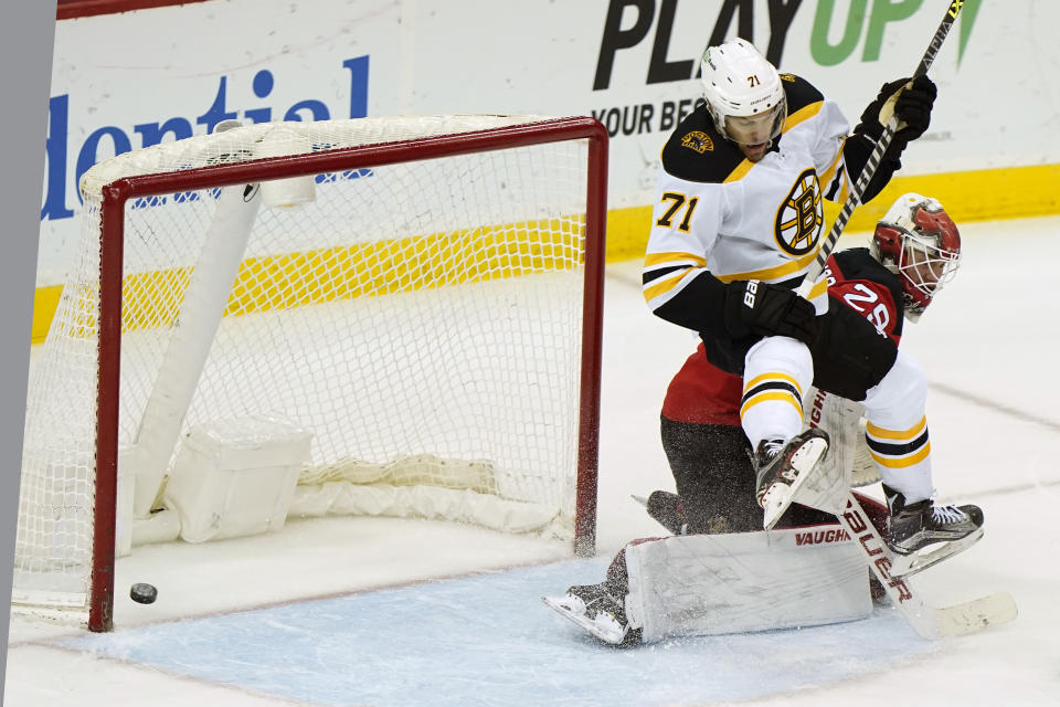 The puck goes in on a shot by Boston Bruins left wing Taylor Hall (71) who leaps above New Jersey Devils goaltender Mackenzie Blackwood (29) during the second period of an NHL hockey game, Tuesday, May 4, 2021, in Newark, N.J. The goal was ruled good after a video review. (AP Photo/Kathy Willens)