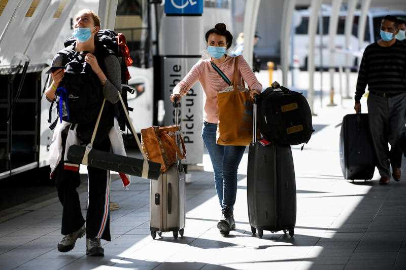 Australian residents returning from India are ushered towards waiting busses for the beginning of their 14-day imposed quarantine after arriving at Sydney International Airport.