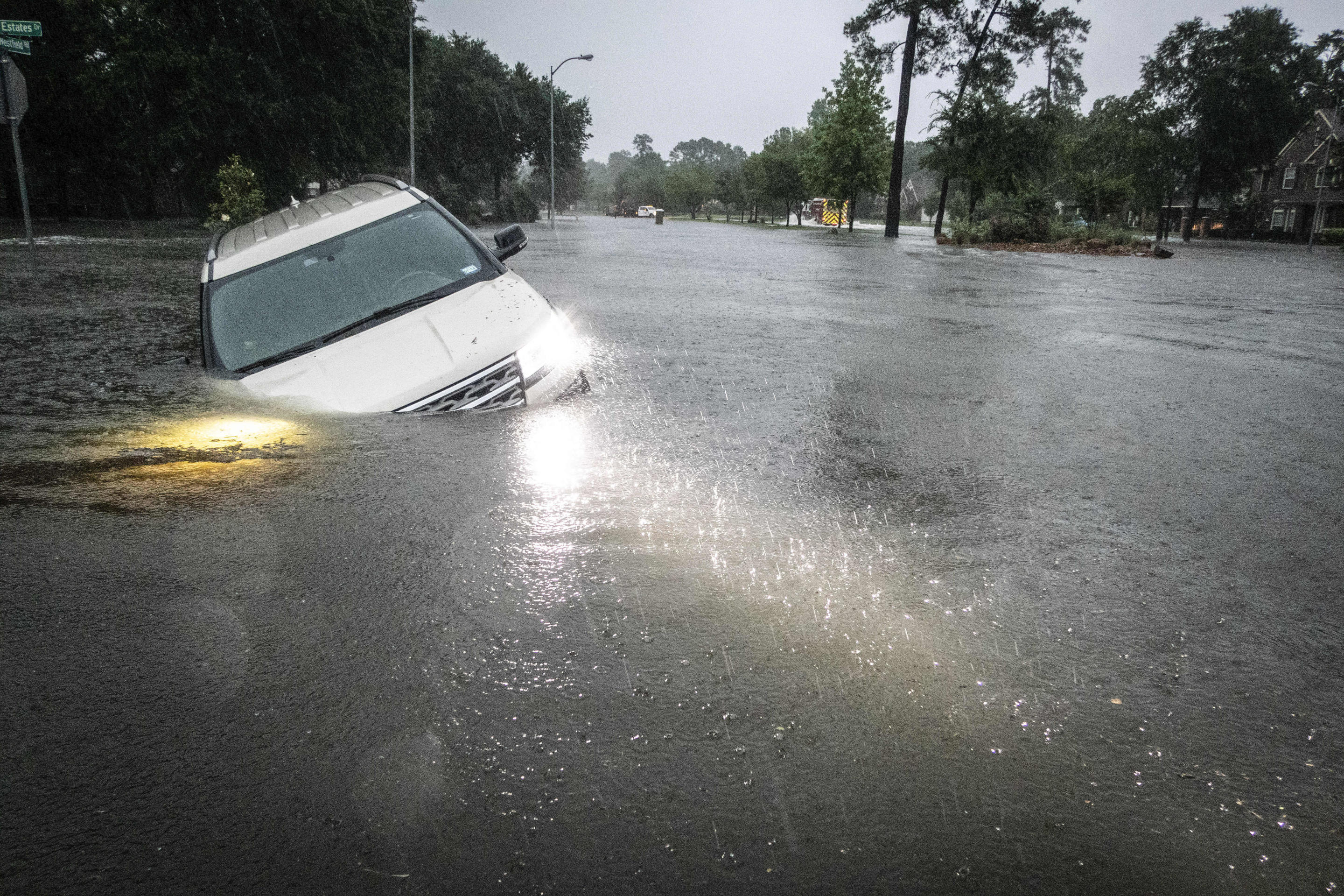 An SUV is stranded in a flooded ditch.