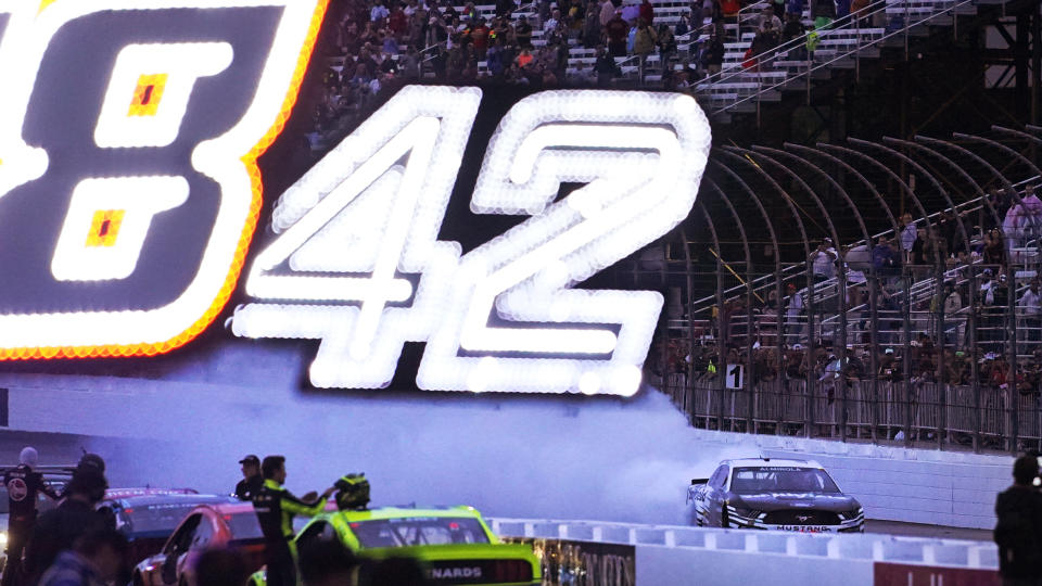 Aric Almirola does a burnout at dusk while celebrating his win in the NASCAR Cup Series auto race Sunday, July 18, 2021, in Loudon, N.H. (AP Photo/Charles Krupa)