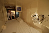 Manager Akiyoshi Kaneko peers inside of a room at the Capsule & Sauna Century Shibuya in Tokyo. (AP Photo/Shizuo Kambayashi)