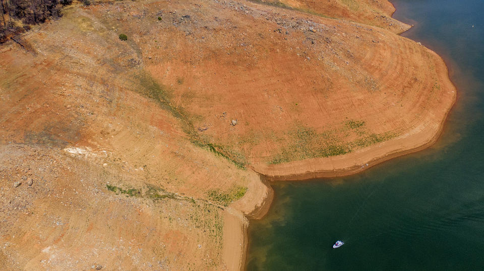 A boat crosses Lake Oroville beneath a dry hillside Saturday, May 22, 2021, in Oroville, Calif. At the time of this photo, the reservoir was at 39 percent of capacity and 46 percent of its historical average. California officials say the drought gripping the U.S. West is so severe it could cause one of the state's most important reservoirs to reach historic lows by late August, closing most boat ramps and shutting down a hydroelectric power plant during the peak demand of the hottest part of the summer. (AP Photo/Noah Berger)