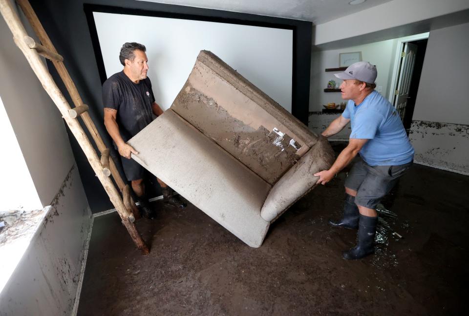 Brandon Hartness and Matt Call carry a soaked couch out of Hartness’ flooded basement in Draper on Friday, Aug. 4, 2023. Draper Mayor Troy Walker declared a state of emergency due to flooding. | Kristin Murphy, Deseret News