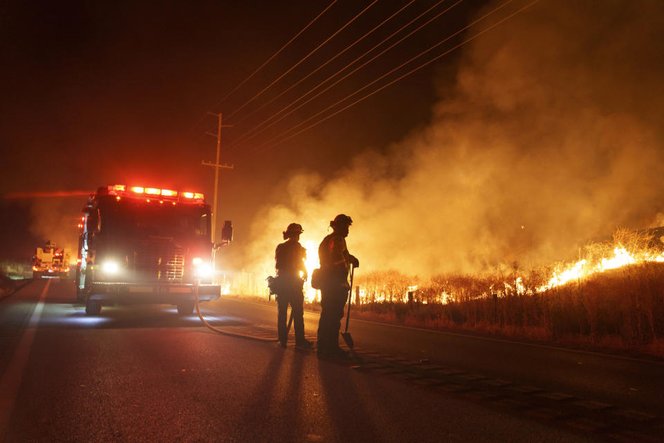 Firefighters monitor as flames consume brush along Gilman Springs Road during the Rabbit Fire late Friday, July 14, 2023, in Moreno Valley, Calif. (AP Photo/Eric Thayer)