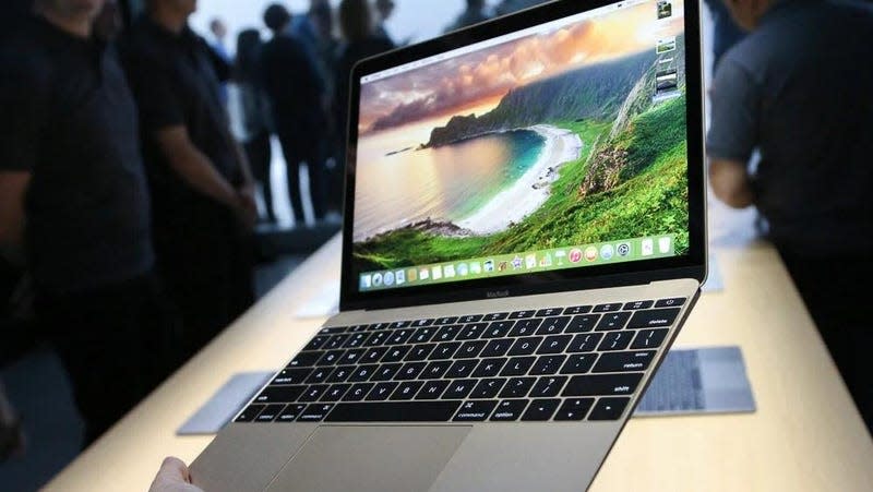 A person holding a 12-inch MacBook showing the main screen.