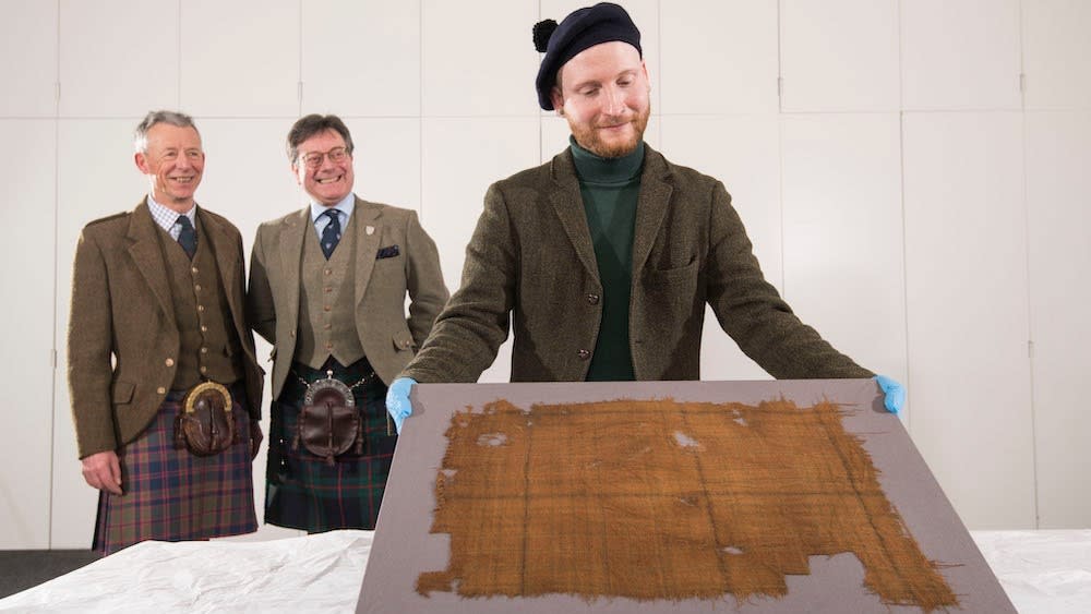  Peter MacDonald, head of research and collections and John McLeish, chair of The Scottish Tartans Authority and James Wylie, an assistant curator at V&A Dundee, examine the faded tartan. 