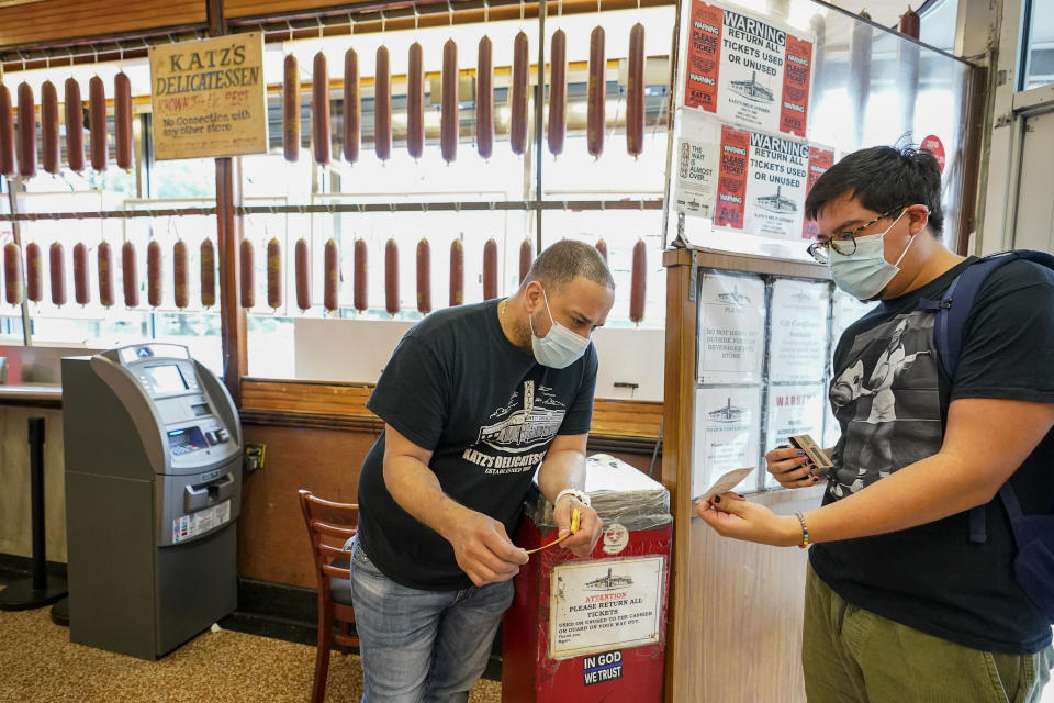 FILE — In this Aug. 17, 2021 file photo, a Katz's Deli employee, left, checks the proof of vaccination from a customer who will be eating inside the restaurant, in New York. New York City's COVID-19 vaccination mandate for restaurants, gyms and entertainment venues is going so well that only 15 businesses have been fined for not enforcing the policy, Mayor Bill de Blasio said Wednesday, Oct. 13, 2021. (AP Photo/Mary Altaffer, File)