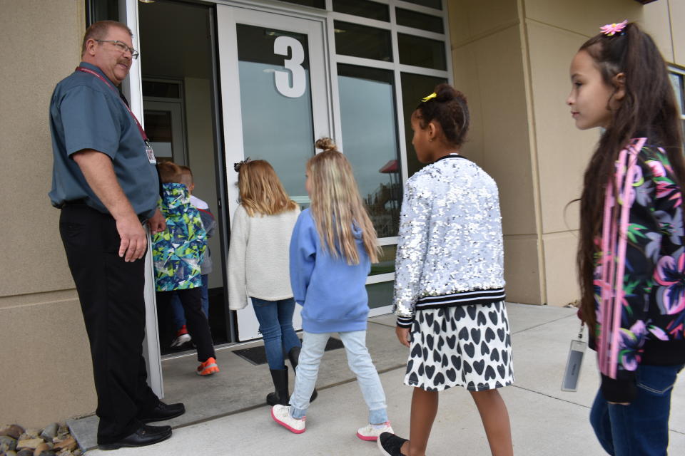 Principal Brad Foss holds the door for students returning from recess at Fox Hills Elementary School, Aug. 26, 2021, in Watford City, N.D., part of McKenzie County, the fastest-growing county in the U.S. School enrollment tripled over the past decade and is expected to double again by 2030, as McKenzie County became the fastest growing county in the U.S. (AP Photo/Matthew Brown)