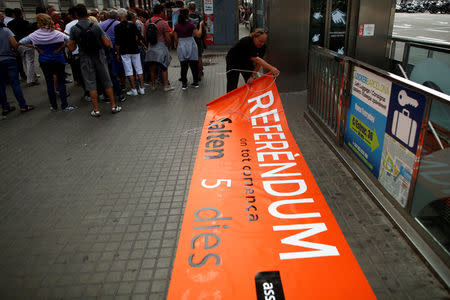 Catalan National Assembly (ANC) member and public worker of the Terrassa's town hall, Pep Rovira, rolls up a banner after Catalan Mossos d'Esquadra officers prohibited his protest in favor of the banned October 1 independence referendum at Catalunya square in Barcelona, Spain, September 26, 2017. The banner reads, "Referendum. Where everything starts. 5 days left". REUTERS/Jon Nazca