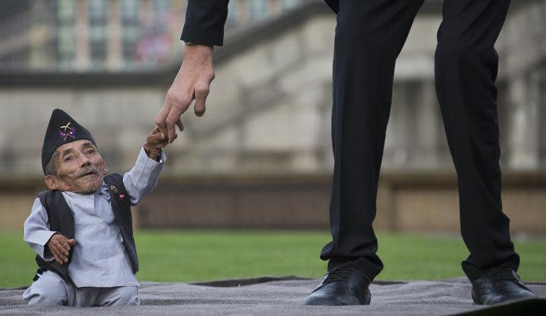 Chandra Bahadur Dangi, from Nepal, (L) the shortest adult to have ever been verified by Guinness World Records, holds the hand of the world's tallest man Sultan Kosen from Turkey, in London on November 13, 2014