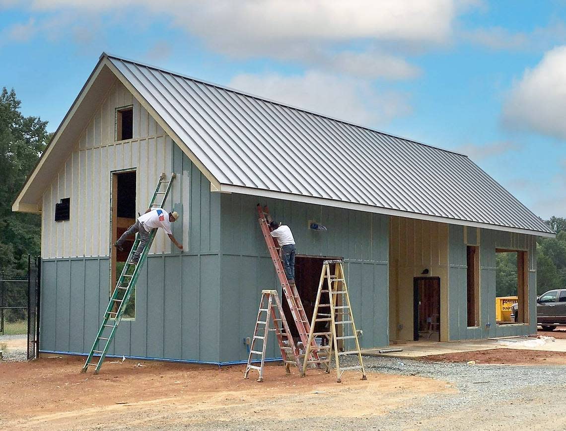 Workers paint the exterior of a new county parks office and garage at Blackwood Farm Park. The $2.8 million park renovation project preserves a historic farmhouse and several outbuildings, and expands the recreation opportunities available in Orange County.