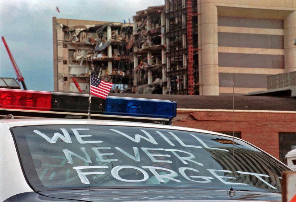 In this April 24, 1995 photo, an Oklahoma City police car decorated with the words, "We will never forget" and a small American flag sits near the Alfred P. Murrah Federal Building in Oklahoma City. The American terrorist who set the blast killed 168 people, including 19 children. Life changed in the U.S. in its aftermath, with new attention paid to domestic terrorism and beefed up security at federal buildings around the country.