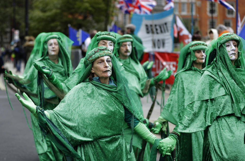 Climate demonstrators pass Brexit banners and flags outside Parliament in London, Tuesday, Oct. 8, 2019. The British government said Tuesday that the chances of a Brexit deal with the European Union were fading fast, as the two sides remained unwilling to shift from their entrenched positions. (AP Photo/Kirsty Wigglesworth)