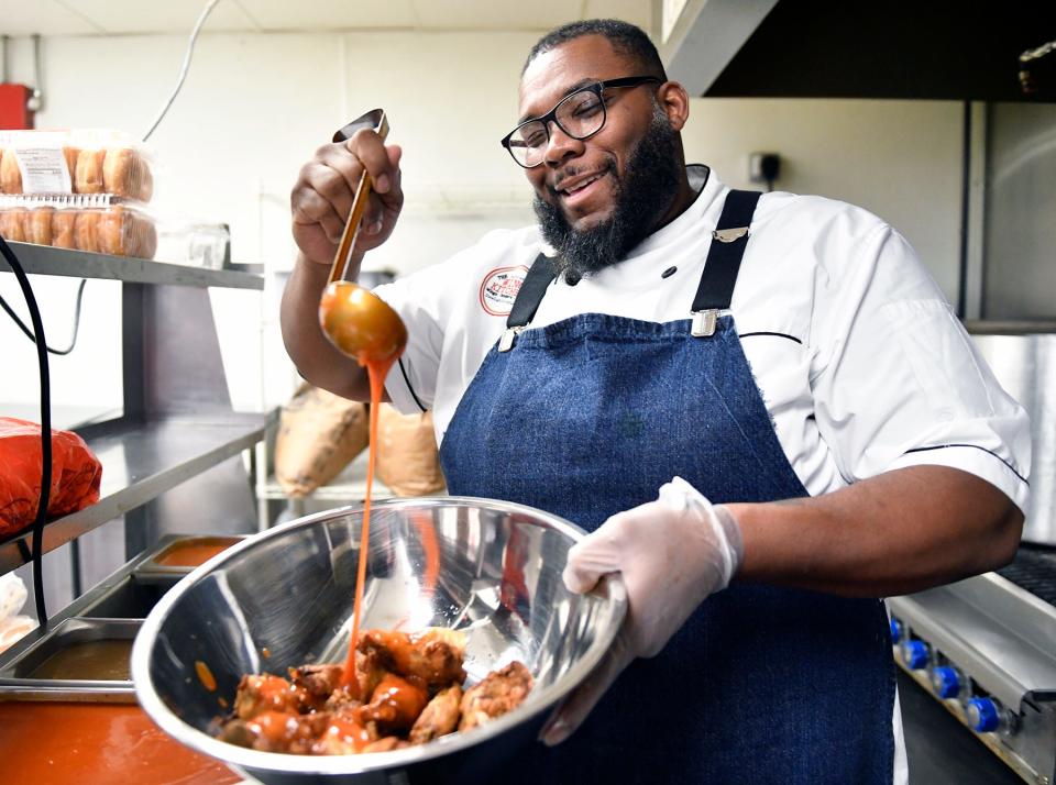 The Wing Kitchen owner Timothy Witcher drizzles his special Buffalo sauce over an order of chicken wings. Witcher is temporarily re-opening his Turnersville location to fulfill Super Bowl wing orders.