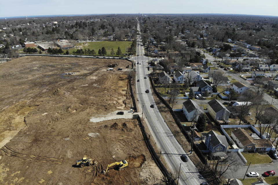 A plot of land that is being developed into multifamily housing, left, is seen in East Northport, N.Y., Thursday, March 16, 2023. Some elected officials from Long Island claim their suburban way of life is threatened by New York Gov. Kathy Hochul's plan to spur more housing construction. They claim it would swamp the area with new apartment buildings and turn it into a "sixth borough" of the city. (AP Photo/Seth Wenig)