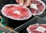 Kazuhiro Shimura, a director at Dentsu Group's Future Creative Center, touches a tail part of a tuna as he demonstrates the 'Tuna Scope' in Miura, Japan