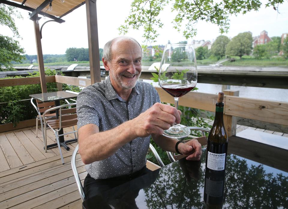 Vino e Vivo owner Tony Callendrello raises a glass of wine on the outside dining patio on the Exeter River.