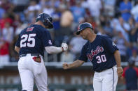 Mississippi's Tim Elko (25) gives a fist-bump to third base coach Mike Clement (30) as he runs to home plate after hitting a home run against Oklahoma in the third inning during the first championship baseball game of the NCAA College World Series Saturday, June 25, 2022, in Omaha, Neb. (AP Photo/John Peterson)