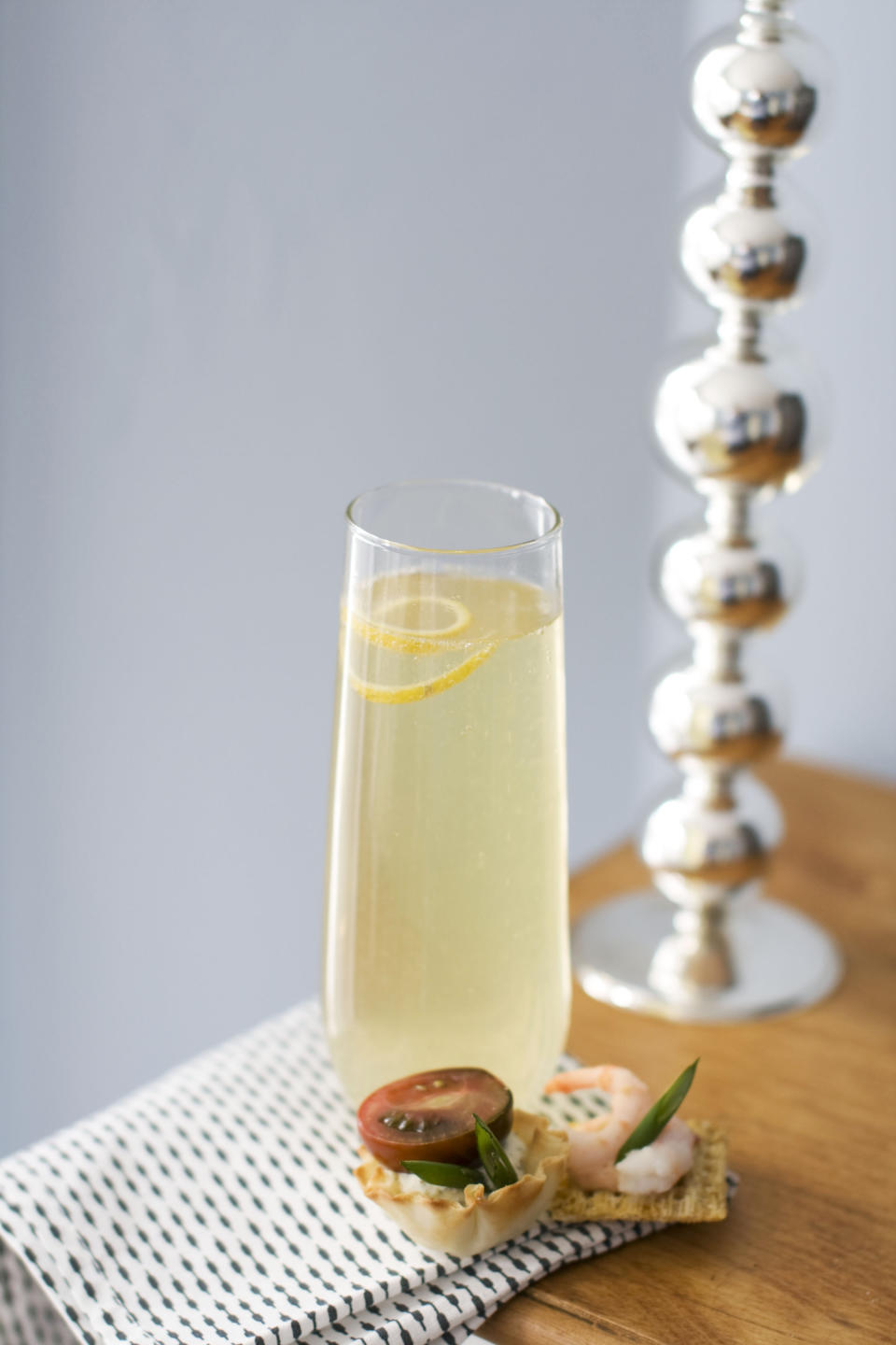 In this image taken on Jan. 28, 2013, a glass of citrus bubbly with a small curl of lemon on top is shown next to canapes on a table in Concord, N.H. (AP Photo/Matthew Mead)