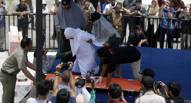 Indonesian women wait to be whipped in front of a baying crowd for