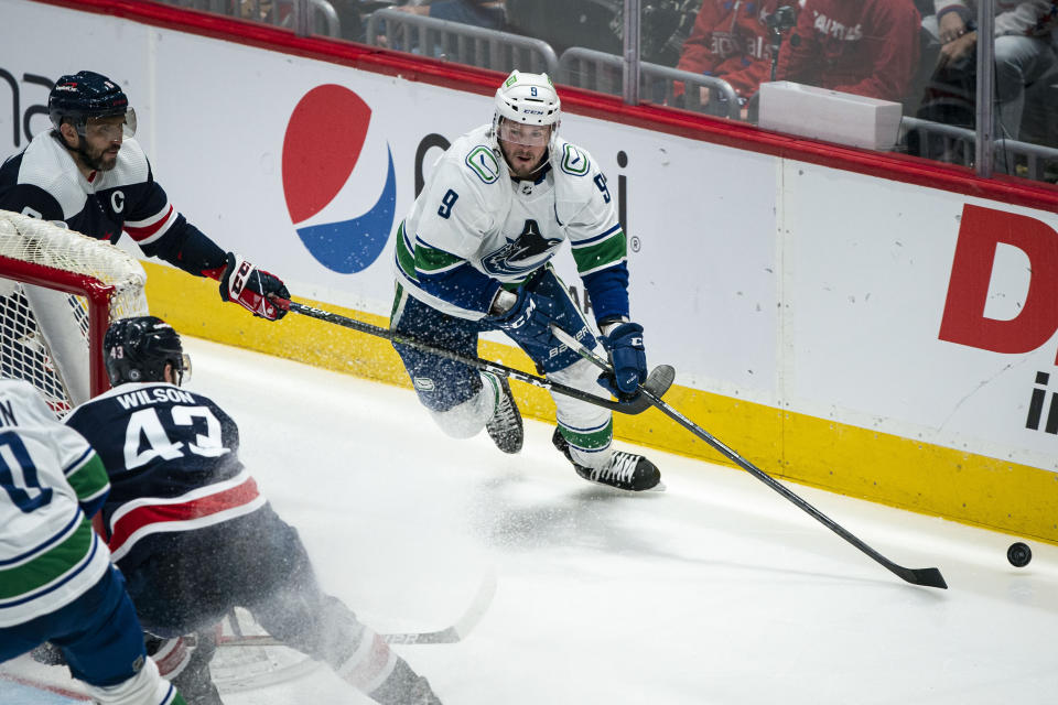 Vancouver Canucks center J.T. Miller (9) moves the puck around the goal past Washington Capitals left wing Alex Ovechkin (8), from Russia, during the third period of an NHL hockey game, Sunday, Jan. 16, 2022, in Washington. (AP Photo/Al Drago)