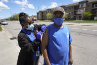 Registered nurse Precious McCormick administers a syringe of Moderna COVID-19 vaccine to Kwame Molette in Detroit, Wednesday, May 12, 2021. In three weeks, more than 40 people have received vaccinations through the program to reach people who normally have little to no access to churches, community centers or other places where vaccines are being given. Mobile care teams consisting of two nurses and a peer support specialist accompany The Salvation Army's Bed & Bread trucks as they cruise Detroit, which lags far behind the state and nearby communities in percentage of people vaccinated. (AP Photo/Paul Sancya)