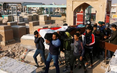 Mourners carry the coffin of a demonstrator who was killed at an anti-government protest, during a funeral at a cemetery in Najaf - Credit: Reuters