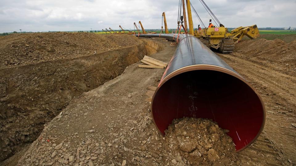 Ein Rohrstück für die Pipeline-Verlänung Opal wird im sächsischen Reinersdorf mit Hilfe von Seitenbaumkränen ins Erdreich verlegt (Archiv).