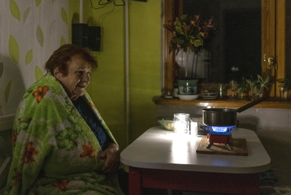 An elderly woman cooks food on a gas burner during a blackout in Kyiv, Ukraine, Monday, Nov. 14, 2022. The situation in Ukraine's capital, Kyiv, and other major cities has deteriorated drastically following the largest missile attack on the country's power grid on Tuesday, Nov. 15, 2022. Ukrainian state-owned grid operator Ukrenergo reported that 40% of Ukrainians were experiencing difficulties, due to damage to at least 15 major energy hubs across the country. (AP Photo/Andrew Kravchenko)