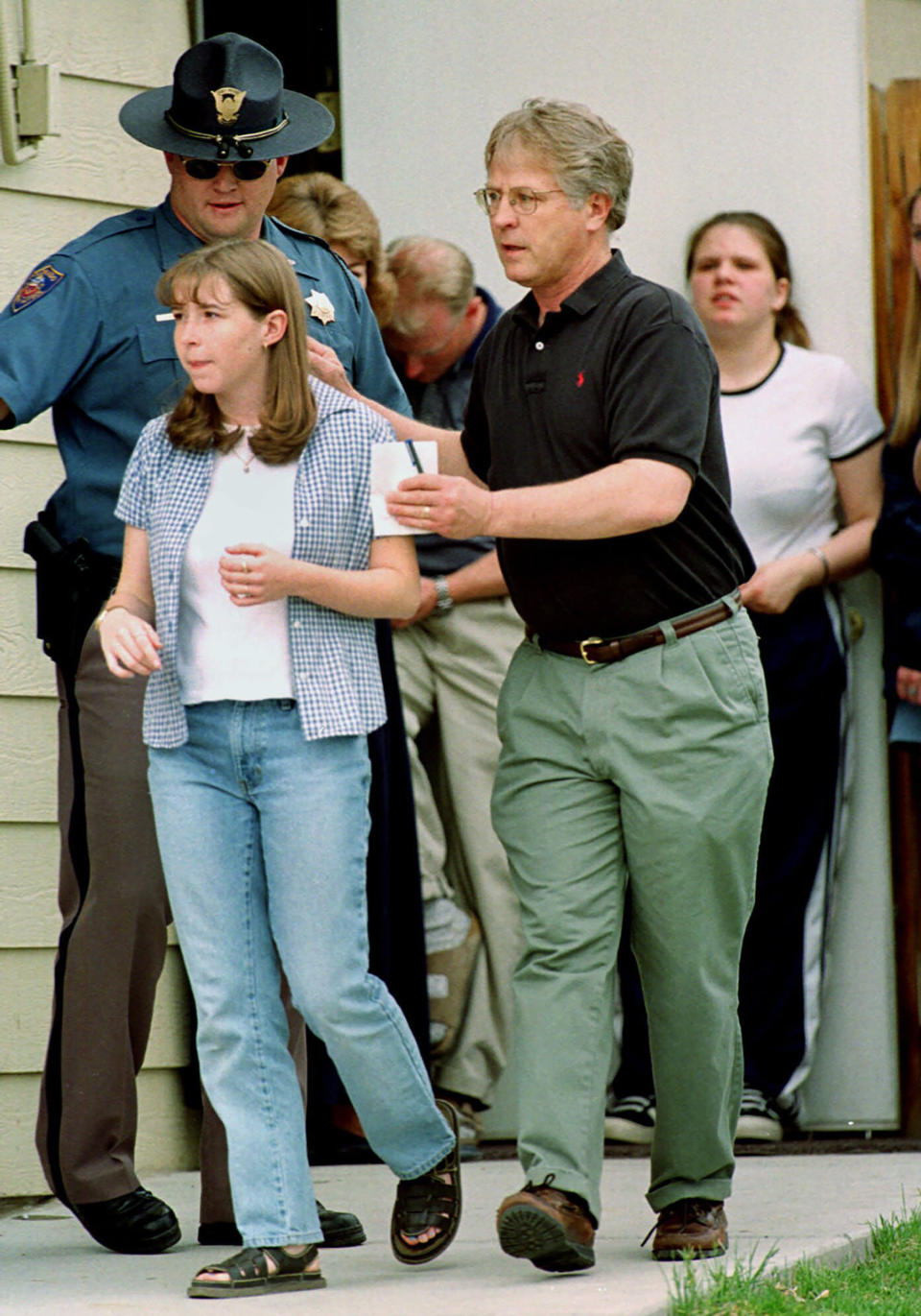 FILE - A student from Columbine High School in Littleton, Colo., left, is led away from a home near the school by a relative after the young woman and more than two dozen other students were evacuated from the school on Tuesday, April 20, 1999. Twenty-five years later, The Associated Press is republishing this story about the attack, the product of reporting from more than a dozen AP journalists who conducted interviews in the hours after it happened. The article first appeared on April 22, 1999. (AP Photo/David Zalubowski, File)