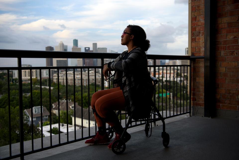 Liza Fisher looks at the skyline while posing for a portrait at her home in Houston on Sept. 5, 2022.  In early July 2020, Liza Fisher of Houston was diagnosed with COVID pneumonia and by the end of the month, she was in a hospital intensive care unit. A week later, she was transferred to a rehab facility where she stayed, other than another two-week hospital stint, until Oct. 13, 2020.  In rehab she lost the ability to walk and began suffering debilitating tremors, for reasons her doctors still don't understand. Now, more than two years after her initial infection, Fisher is making slow, incremental progress and hoping for no more setbacks.