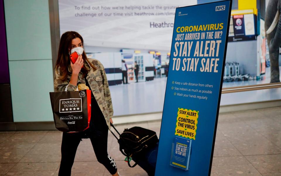 A newly-arrived passenger walks past a sign offering advice about coronavirus at Heathrow Airport - AFP