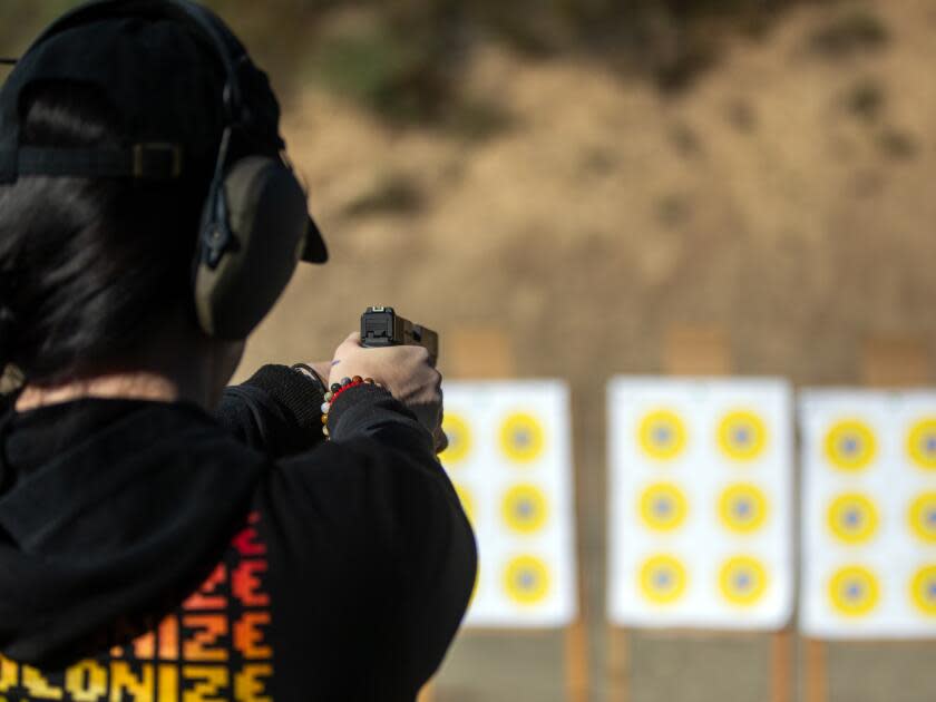 Nikki Shrieves fires a pistol at a row of paper bull's-eye targets