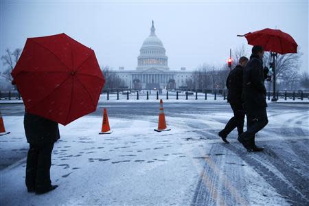 People walk near the U.S. Capitol in early morning snow in Washington, March 3, 2014. REUTERS/Jonathan Ernst