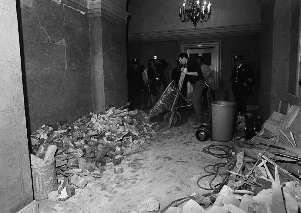 Workers begin the job of cleaning up debris in a hallway on the Senate side of the Capitol on March 1, 1971, following the explosion of a bomb nearby. Officials reported extensive damage but no injuries.