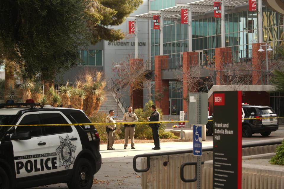 Police officers stand in front of the Student Union a day after three people died and one person