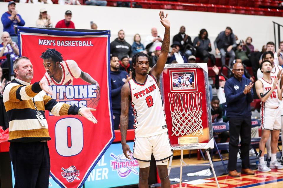 Detroit Mercy guard Antoine Davis waves as University president Donald Taylor, left, helps unveil the banner during Davis' jersey number retirement ceremony at Calihan Hall in Detroit on Saturday, Feb. 25, 2023.