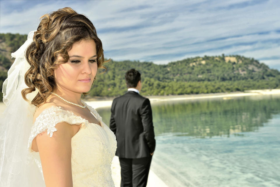 Sad bride on beach with groom