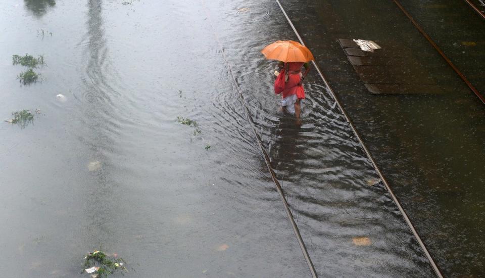 An Indian woman wades through waterlogged railway tracks in Mumbai (Getty)
