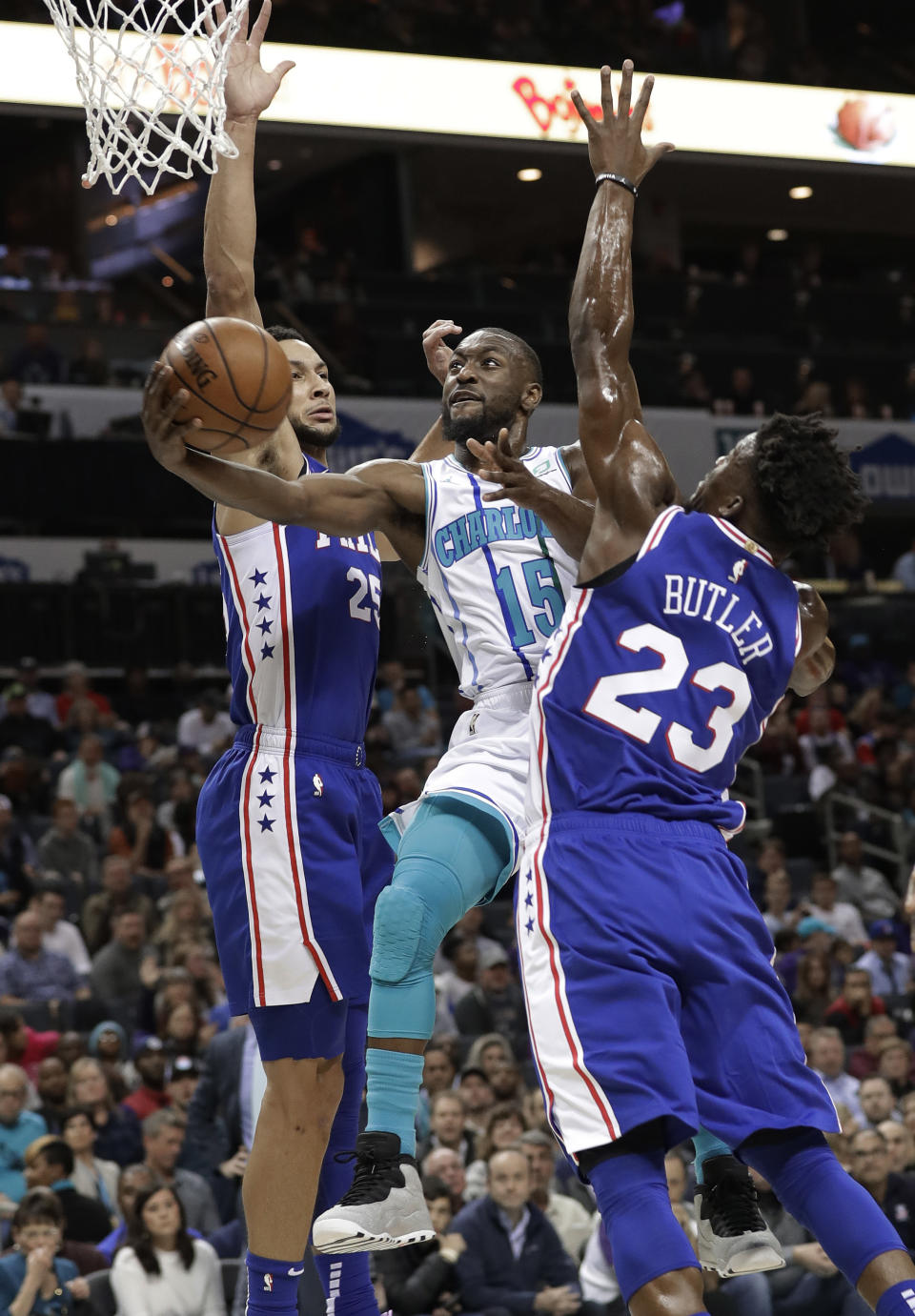 Charlotte Hornets' Kemba Walker (15) drives between Philadelphia 76ers' Jimmy Butler (23) and Ben Simmons (25) during the first half of an NBA basketball game in Charlotte, N.C., Saturday, Nov. 17, 2018. (AP Photo/Chuck Burton)