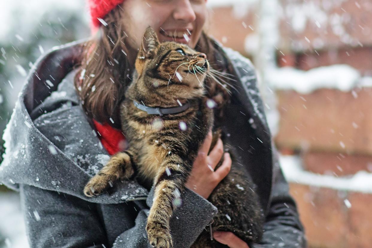 teenage girl holding cat with hypothermia in the snow