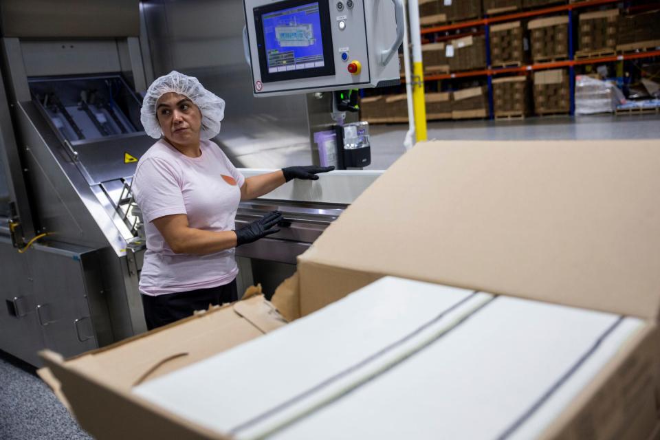 Boxed Water employees work to prepare cartons as they feed into an automated machine Friday, Sept. 16, 2023, in Hollland, MI.